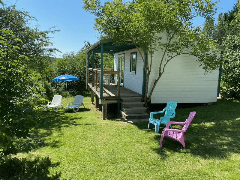 Terrasse en bois couverte avec salon de jardin et parasol, des chalets Pommier 4 personnes climatisés. Locations de chalets en Ariège