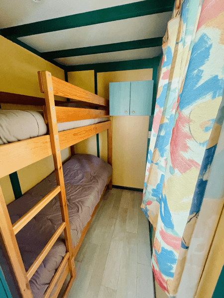 Chambre avec lit superposé des chalets Pommier 4 personnes climatisés. Locations de chalets en Occitanie