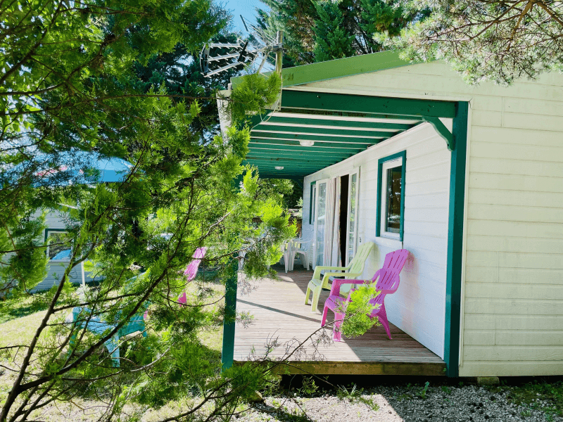 Terrasse en bois couverte avec salon de jardin et parasol. Location Chalets en Ariège, chalets Epicéa conforts 6 personnes