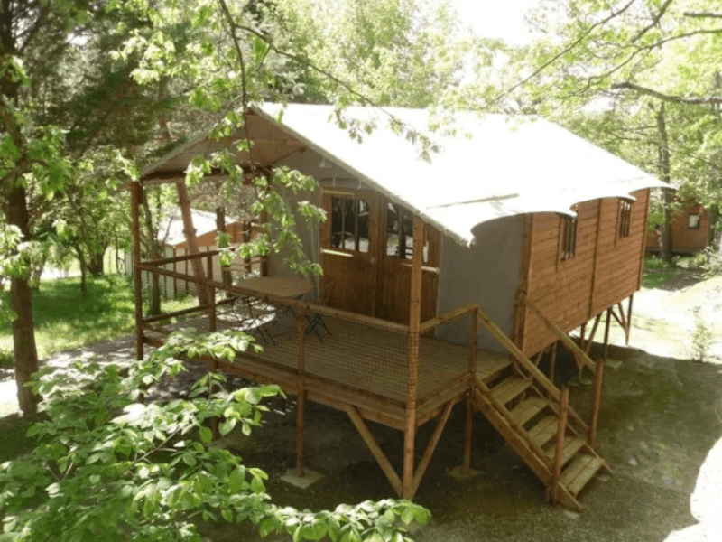 La grande terrasse en bois couverte du Lodge Èrable Confort. Le glamping à Camon en Ariège
