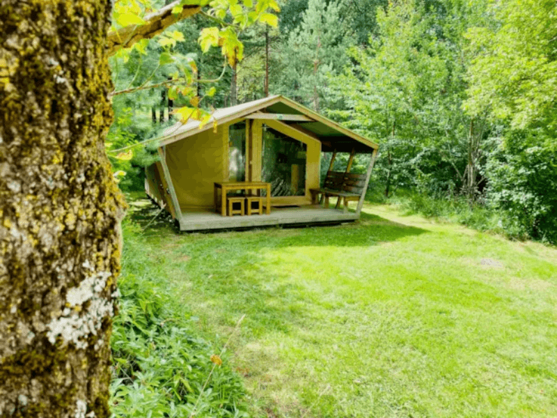 Terrasse en bois couverte avec salon de jardin en bois du Lodge Noisetier Confort. Le glamping à Camon en Ariège