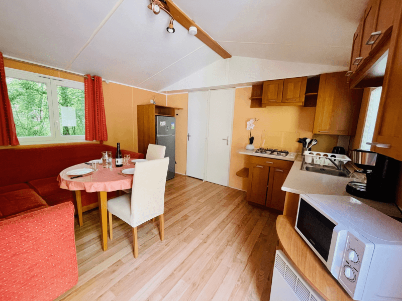 Kitchen/living area with bench and table. Mobile home rental in Ariège, comfort Chêne mobile home 4 people