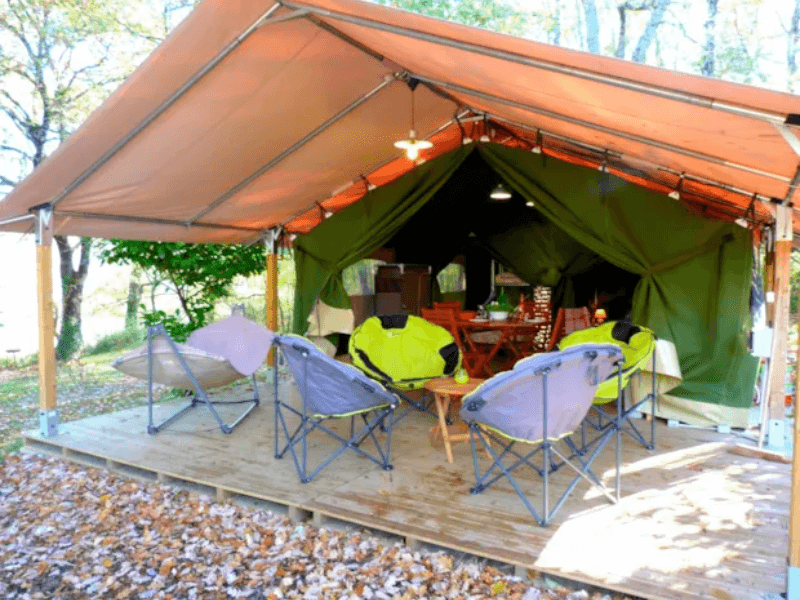 Grande terrasse en bois couverte avec salon de jardin en bois, de la tente Safari Accacia Standard. Le glamping en Occitanie
