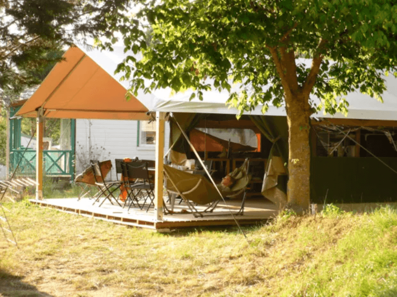 Large covered wooden terrace with wooden garden furniture, from the Acacia Safari Tent Standard. Glamping in Ariège