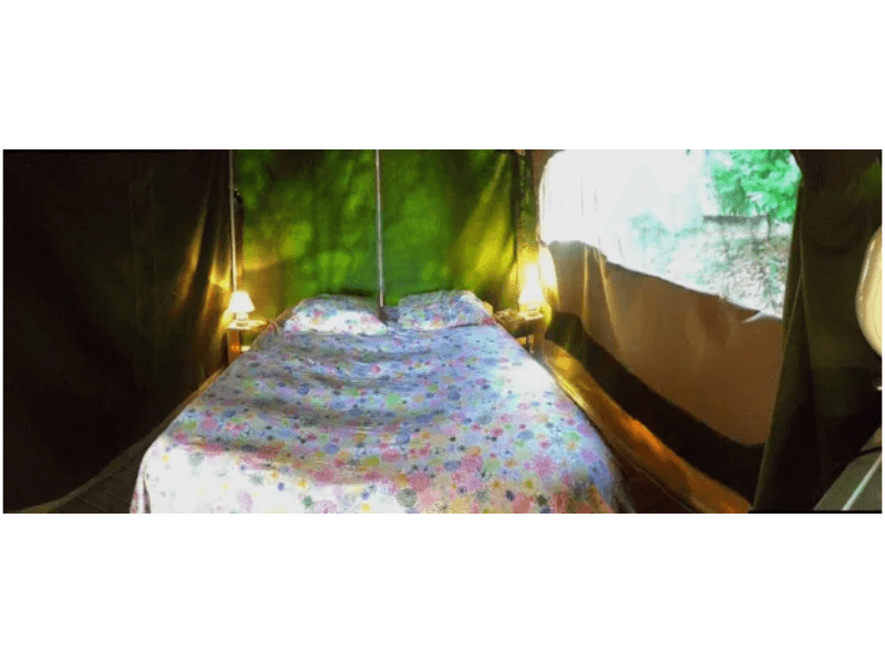 Chambre avec lit double de la tente Safari Accacia Standard. Le glamping en Occitanie